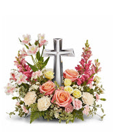 Coral roses, yellow spray roses, pink alstroemeria, creme carnations, mini pink carnations, hot pink snapdragons, and floral greenery with a large crystal cross on top of the arrangement