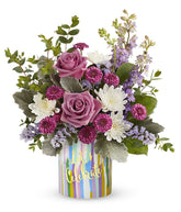 Lavender roses arranged with purple button chrysanthemums, lavender larkspur, lavender sinuata statice, and floral greens in a keepsake