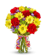 Yellow daisies, red carnations and green button poms in a glass vase
