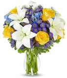 Yellow roses, blue delphinium and white lilies in a vase for Mothers Day