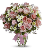 Floral arrangement featuring pink roses, white roses, mini carnations, and green poms in a clear glass vase with a bow.