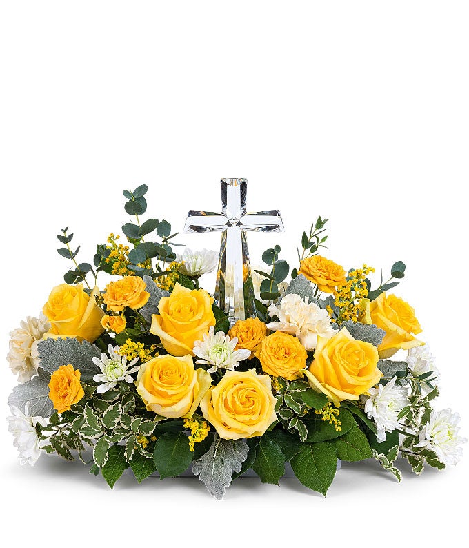 A stunning arrangement featuring yellow roses (deluxe & premium only), yellow spray roses, light yellow carnations, white mums, yellow solidago, and floral greens, elegantly accented with a crystal cross. This vibrant mix offers a bright and uplifting dis