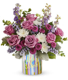 Lavender roses arranged with purple button chrysanthemums, lavender larkspur, lavender sinuata statice, and floral greens in a keepsake 
