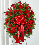 A heartfelt standing spray featuring red roses and carnations with floral greens, arranged by your local florist and hand-delivered with a decorative red bow.